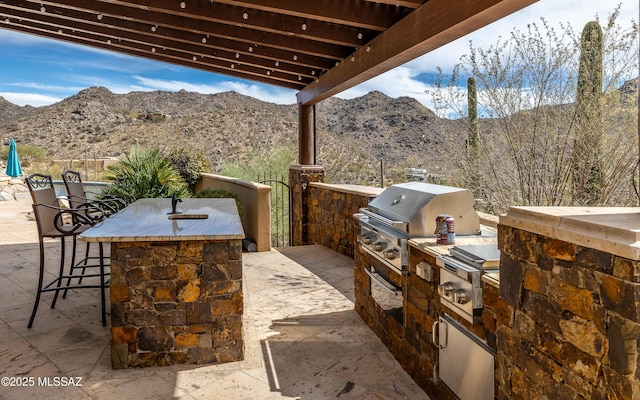 view of patio / terrace featuring outdoor wet bar, area for grilling, a mountain view, and grilling area