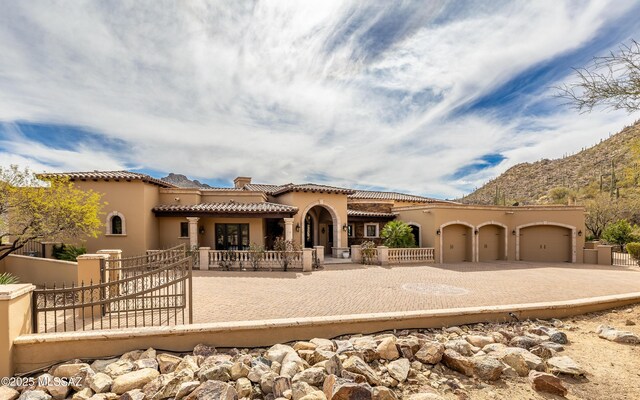 mediterranean / spanish house featuring a tiled roof, an attached garage, and fence