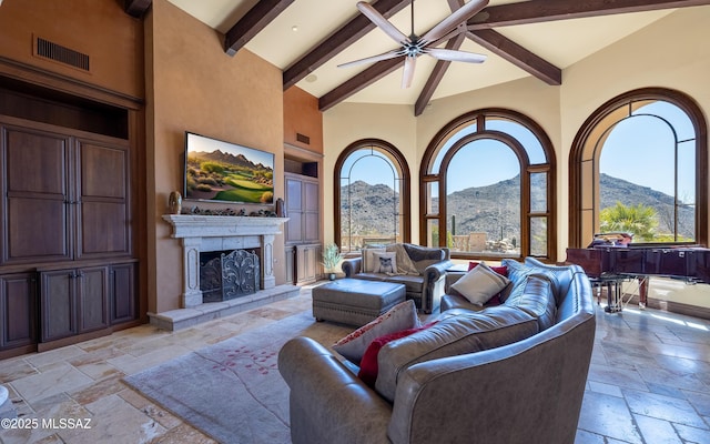 living area featuring visible vents, a fireplace with raised hearth, beamed ceiling, stone tile flooring, and high vaulted ceiling