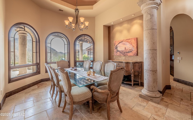 dining room featuring decorative columns, baseboards, a notable chandelier, and stone tile flooring