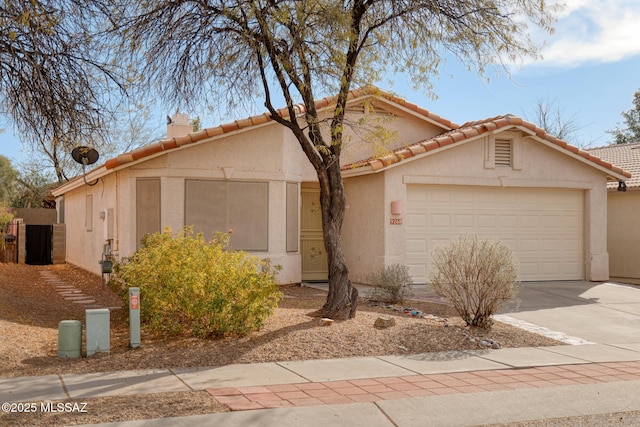 view of front of home with a garage, a tiled roof, concrete driveway, and stucco siding