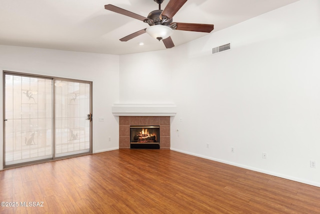 unfurnished living room featuring a fireplace, visible vents, a ceiling fan, wood finished floors, and baseboards