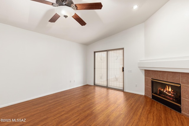 unfurnished living room with lofted ceiling, a tile fireplace, wood finished floors, a ceiling fan, and baseboards