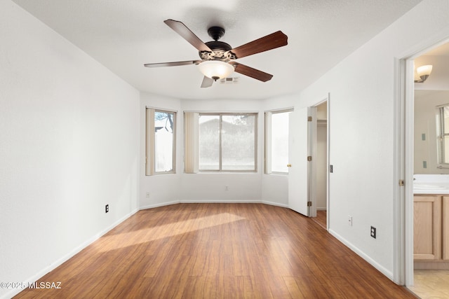 unfurnished bedroom with ensuite bathroom, a sink, visible vents, baseboards, and light wood finished floors