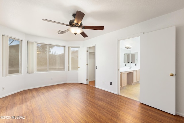 unfurnished room with a ceiling fan, light wood-type flooring, visible vents, and baseboards