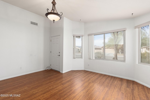 empty room with visible vents, baseboards, and wood finished floors