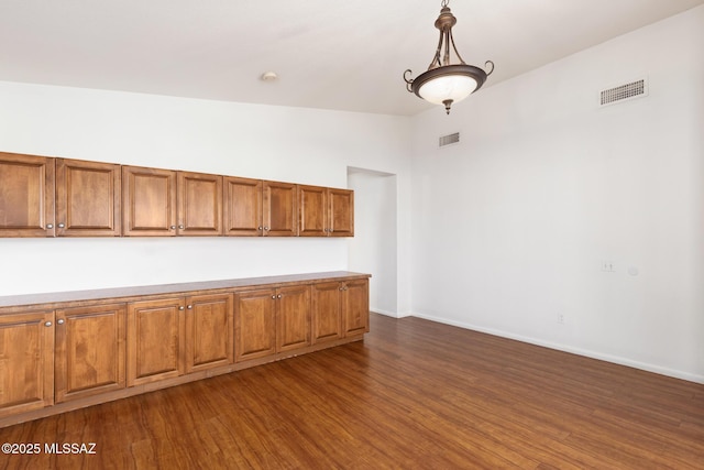 interior space with brown cabinets, dark wood-style flooring, visible vents, and vaulted ceiling