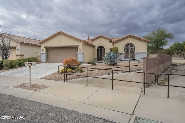 mediterranean / spanish home featuring a fenced front yard, an attached garage, a tile roof, concrete driveway, and stucco siding