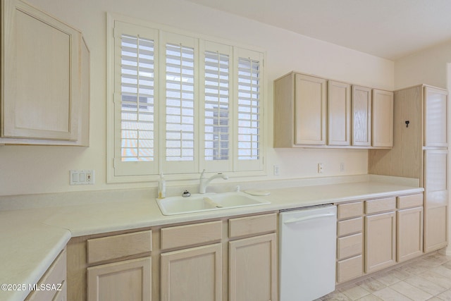 kitchen featuring light countertops, light brown cabinets, white dishwasher, and a sink