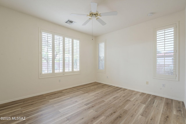 spare room with light wood finished floors, ceiling fan, visible vents, and baseboards