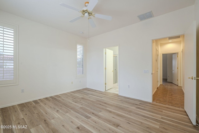 unfurnished bedroom with light wood finished floors, baseboards, visible vents, and ensuite bathroom