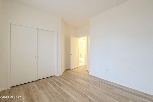 unfurnished bedroom featuring a closet, light wood-type flooring, and baseboards