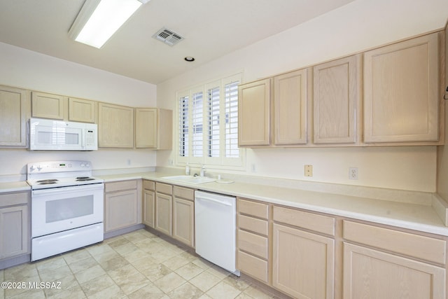 kitchen featuring light countertops, visible vents, light brown cabinets, a sink, and white appliances