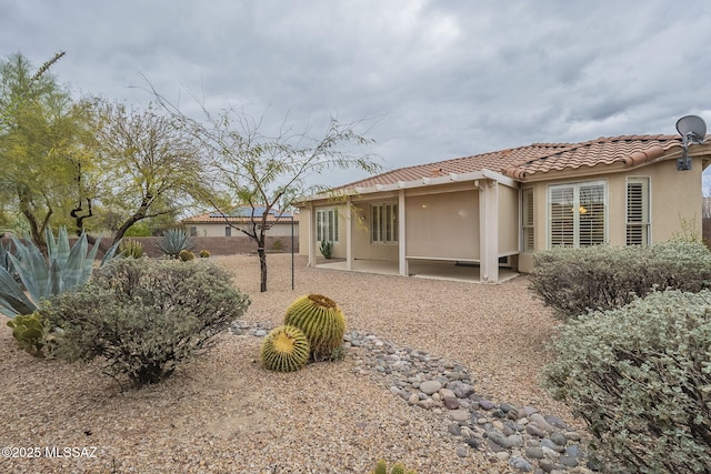 back of property featuring a patio area, a tile roof, fence, and stucco siding