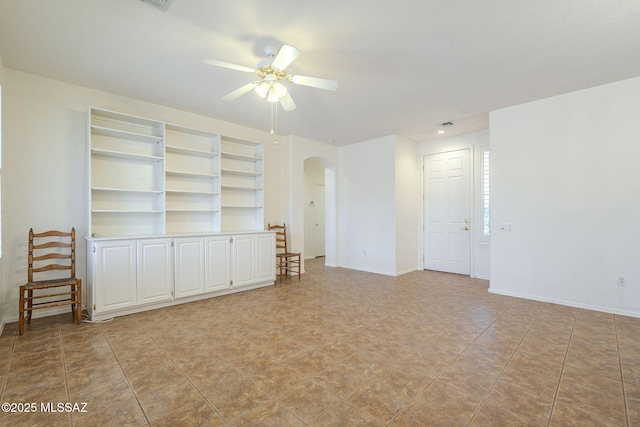 spare room with ceiling fan, arched walkways, and baseboards