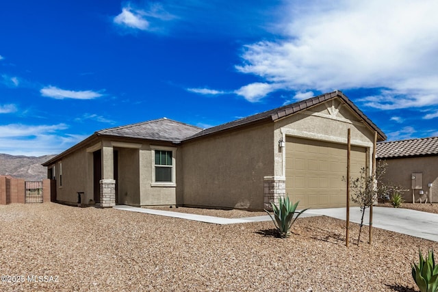 single story home with a garage, driveway, a mountain view, and stucco siding