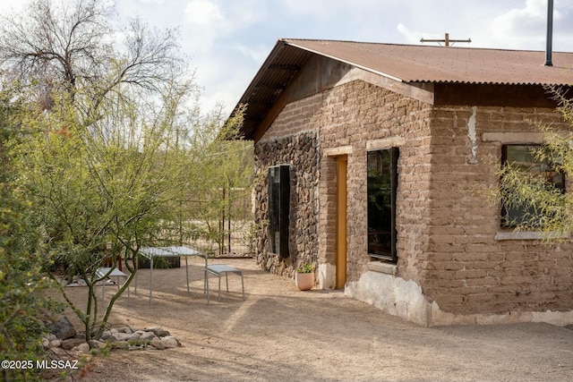 view of side of property with stone siding and a patio