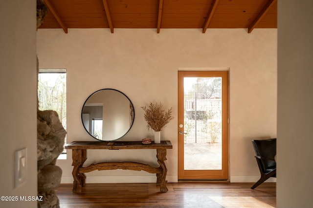 interior space with lofted ceiling with beams, wooden ceiling, wood finished floors, and baseboards