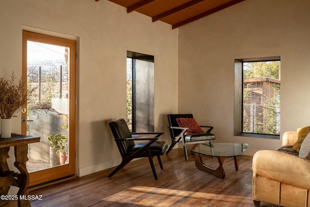 living area featuring vaulted ceiling with beams, wood finished floors, and baseboards