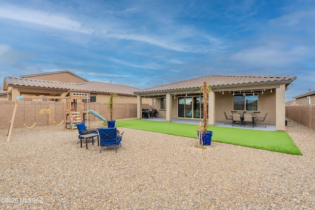 back of house with stucco siding, a patio, a playground, and a fenced backyard