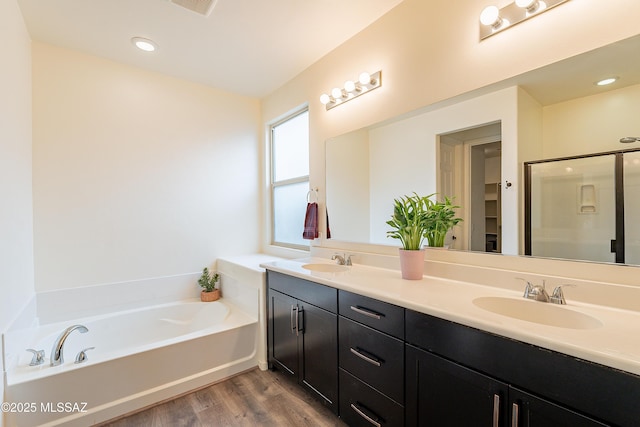 bathroom featuring a bath, a shower stall, wood finished floors, and a sink