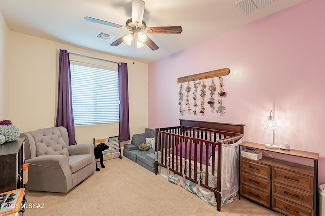 carpeted bedroom featuring a crib, a ceiling fan, and visible vents