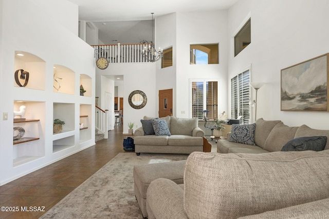 living room with stairs, dark tile patterned flooring, built in shelves, and a chandelier