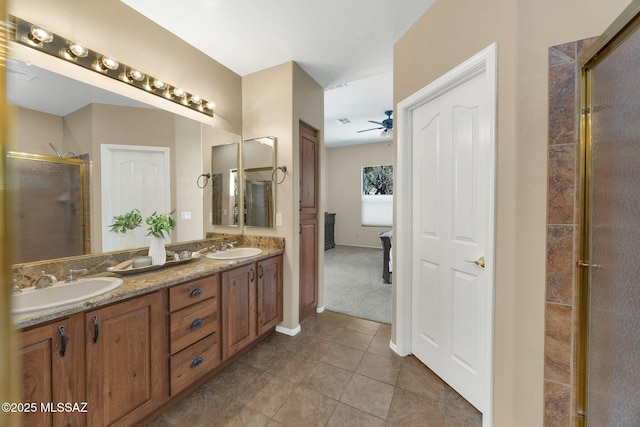 full bath with a sink, a ceiling fan, double vanity, and a shower stall