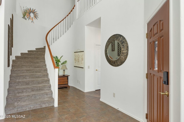 foyer entrance featuring baseboards, stairs, and a towering ceiling