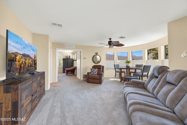 living area with carpet, visible vents, and ceiling fan