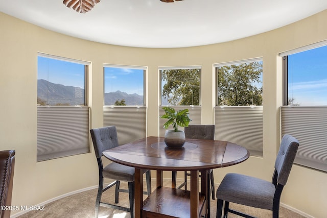 carpeted dining area with a mountain view and baseboards