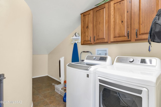 clothes washing area featuring baseboards, cabinet space, and washing machine and dryer