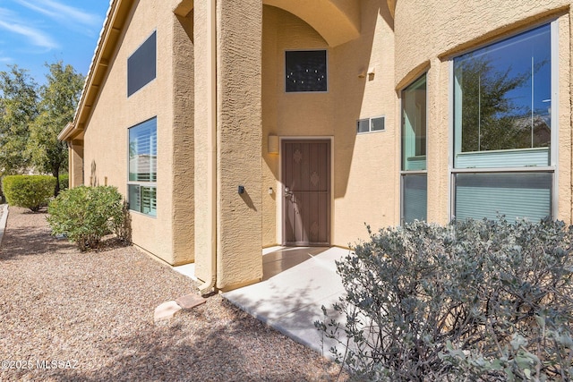 property entrance featuring stucco siding and visible vents