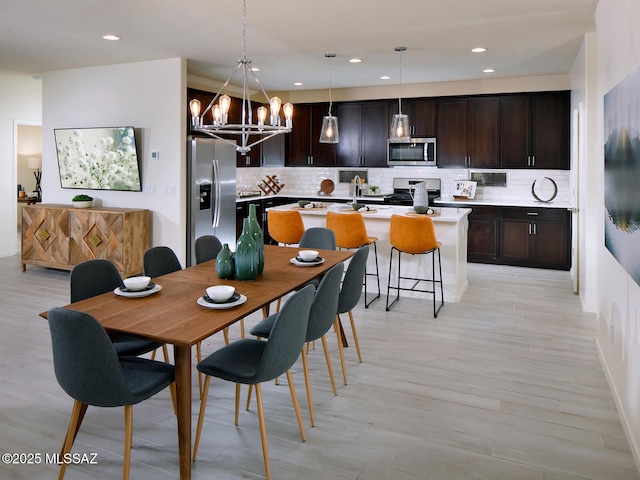 dining room with a notable chandelier, recessed lighting, and light wood-type flooring