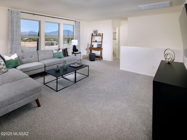 carpeted living room with visible vents, a mountain view, and baseboards