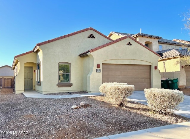 mediterranean / spanish-style house with concrete driveway, an attached garage, a tile roof, and stucco siding