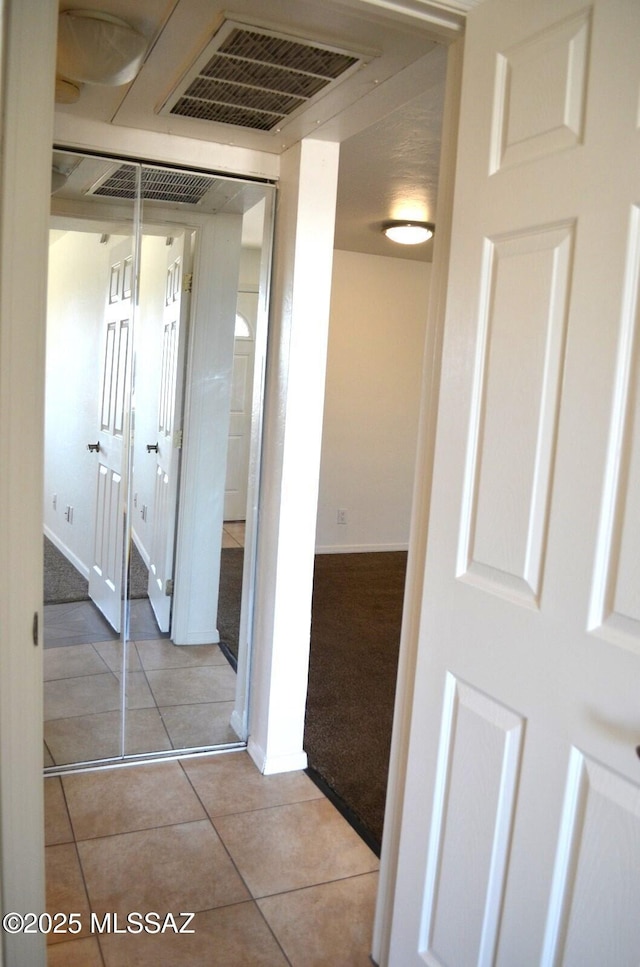 corridor with light tile patterned floors, visible vents, light carpet, and baseboards