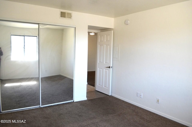 unfurnished bedroom with visible vents, baseboards, a closet, and carpet flooring