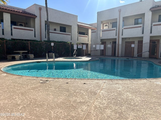view of swimming pool featuring fence and a hot tub