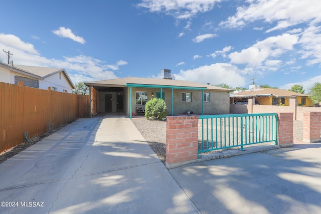 view of front of house featuring fence private yard, an attached carport, and concrete driveway