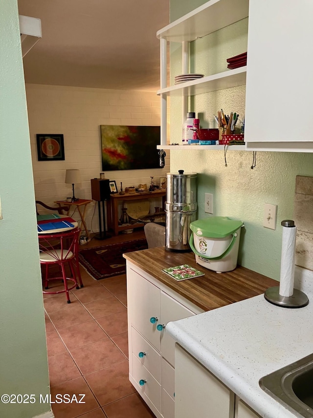 kitchen featuring open shelves, light tile patterned floors, and white cabinets