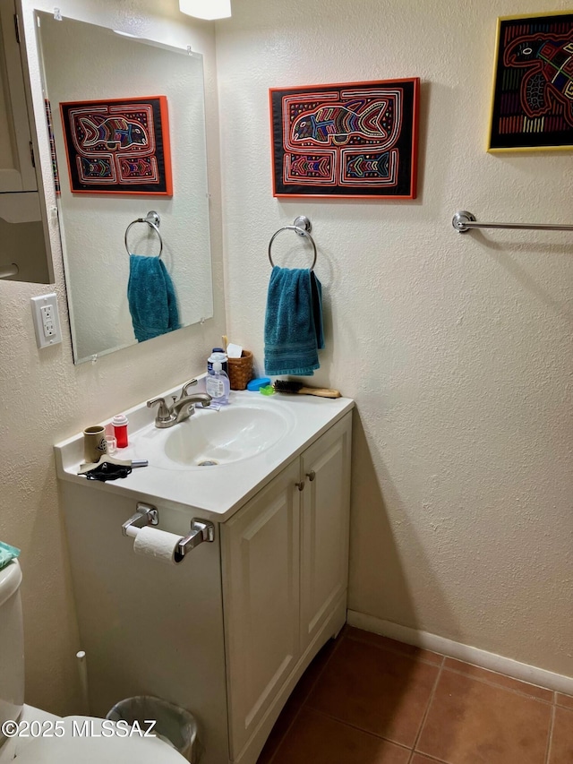 half bath featuring tile patterned flooring, vanity, and baseboards