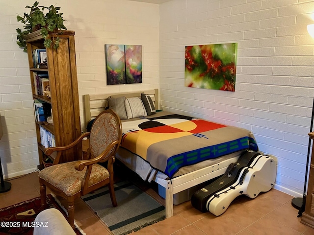 bedroom featuring brick wall and tile patterned flooring