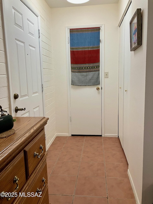 doorway with tile patterned flooring and baseboards