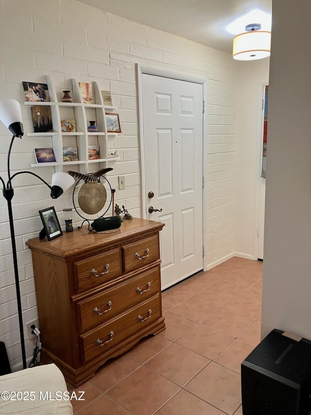 interior space featuring brick wall and light tile patterned flooring