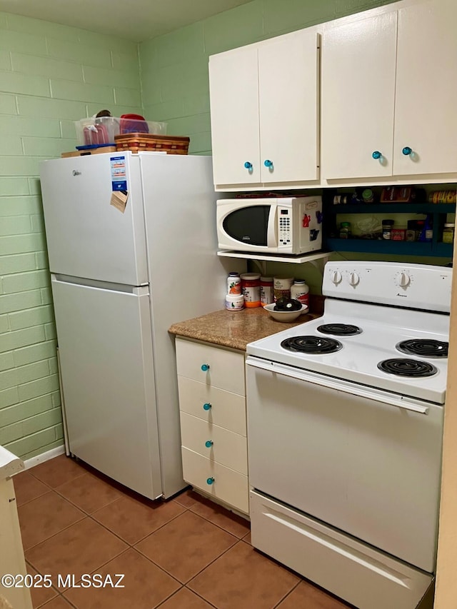 kitchen with white appliances, light tile patterned floors, and white cabinets