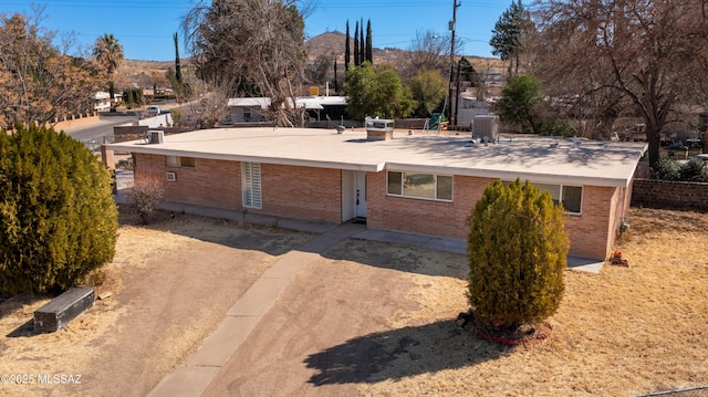 view of front of property featuring dirt driveway, brick siding, and central AC unit