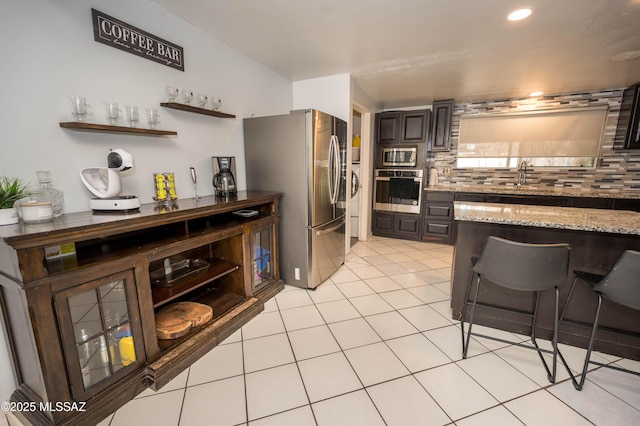 2724 N Green Pl, Nogales, AZ 85621 - kitchen with light stone counters, backsplash, appliances with stainless steel finishes, light tile patterned flooring, and a sink
