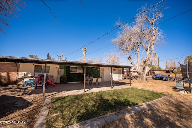 2724 N Green Pl, Nogales, AZ 85621 - back of property featuring a yard, brick siding, a trampoline, and a patio