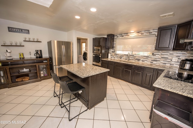 2724 N Green Pl, Nogales, AZ 85621 - kitchen featuring a center island, light tile patterned floors, decorative backsplash, appliances with stainless steel finishes, and a sink